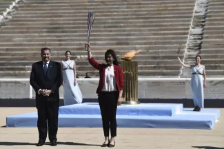 La nageuse Imoto Naoko reçoit la flamme olympique des mains du président du Comité olympique grec, Spyros Capralos, ce jeudi.


