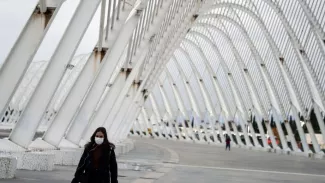 Une femme portant un masque protecteur se promène sous la structure Agora au Complexe sportif olympique, à Athènes en Grèce, le 2 décembre 2020.


