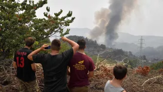 Des habitants regardent la fumée s'élever d'une colline près du village de Kourkouli, dans le nord de l'île d'Eubée, le 5 août 2021, alors que les pompiers grecs luttent pour maîtriser deux incendies majeurs qui font rage près d'Olympie et sur l'île d'Eubée. LOUISA GOULIAMAKI / AFP


