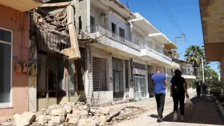 Des personnes passent devant une maison endommagée, suite à un tremblement de terre sur l'île de Crète, dans la ville d'Arkalochori, en Grèce, le 27 septembre 2021. STEFANOS RAPANIS / REUTERS


