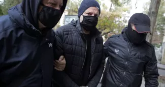 L'acteur grec et ancien directeur du Théâtre national de Grèce Dimitris Lignadis escorté par des policiers en civil alors qu'il entre dans le bureau du procureur à Athènes, en Grèce, le 21 février 2021.