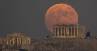 La pleine lune se lève derrière la colline de l'Acropole et l'ancien temple du Parthénon, à Athènes, en Grèce, le mardi 8 novembre 2022. — © Petros Giannakouris / keystone-sda.ch


