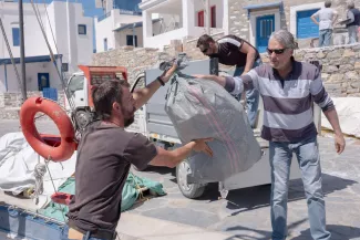 Angelos Vavlekis remet un sac de déchets en plastique, ramassés sur les plages d’Amorgos à l’initiative de l’association Fisher, à son président, Michalis Krosman, à Katapola (Grèce), le 4 avril 2024.