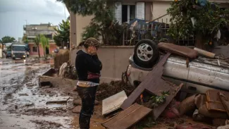 Une femme se prend la tête entre les mains à la vue d'une voiture renversée par les inondations qui ont touché la grande banlieue d'Athènes, le 16 novembre 2017


