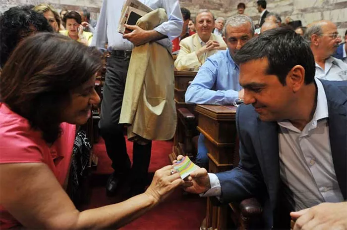 La ministre déléguée à la Solidarité sociale, Theno Photiou, montre la nouvelle Carte de Solidarité au premier ministre Alexis Tsipras. 